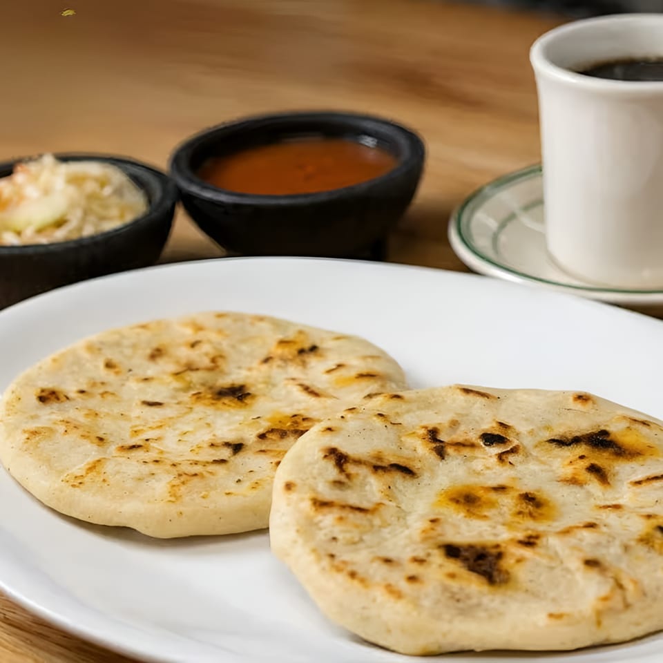 Two grilled flatbreads served with dipping sauces and coffee on a wooden restaurant table.
